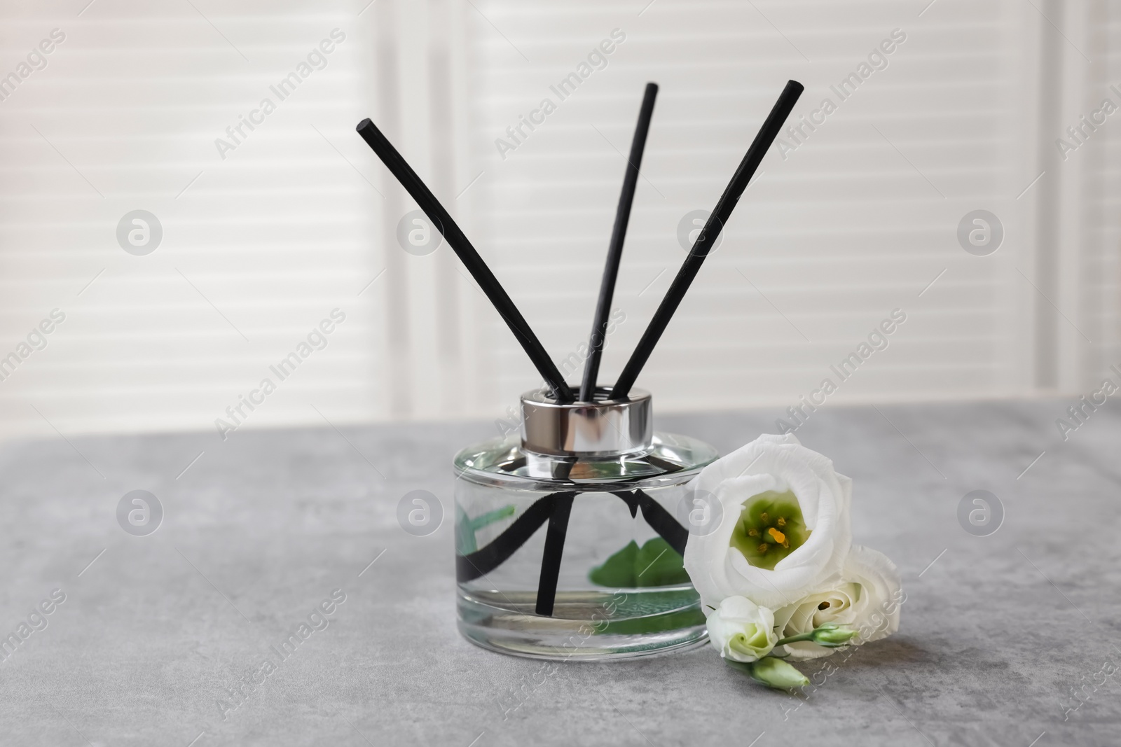 Photo of Reed diffuser and eustoma flowers on gray marble table