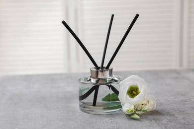 Reed diffuser and eustoma flowers on gray marble table