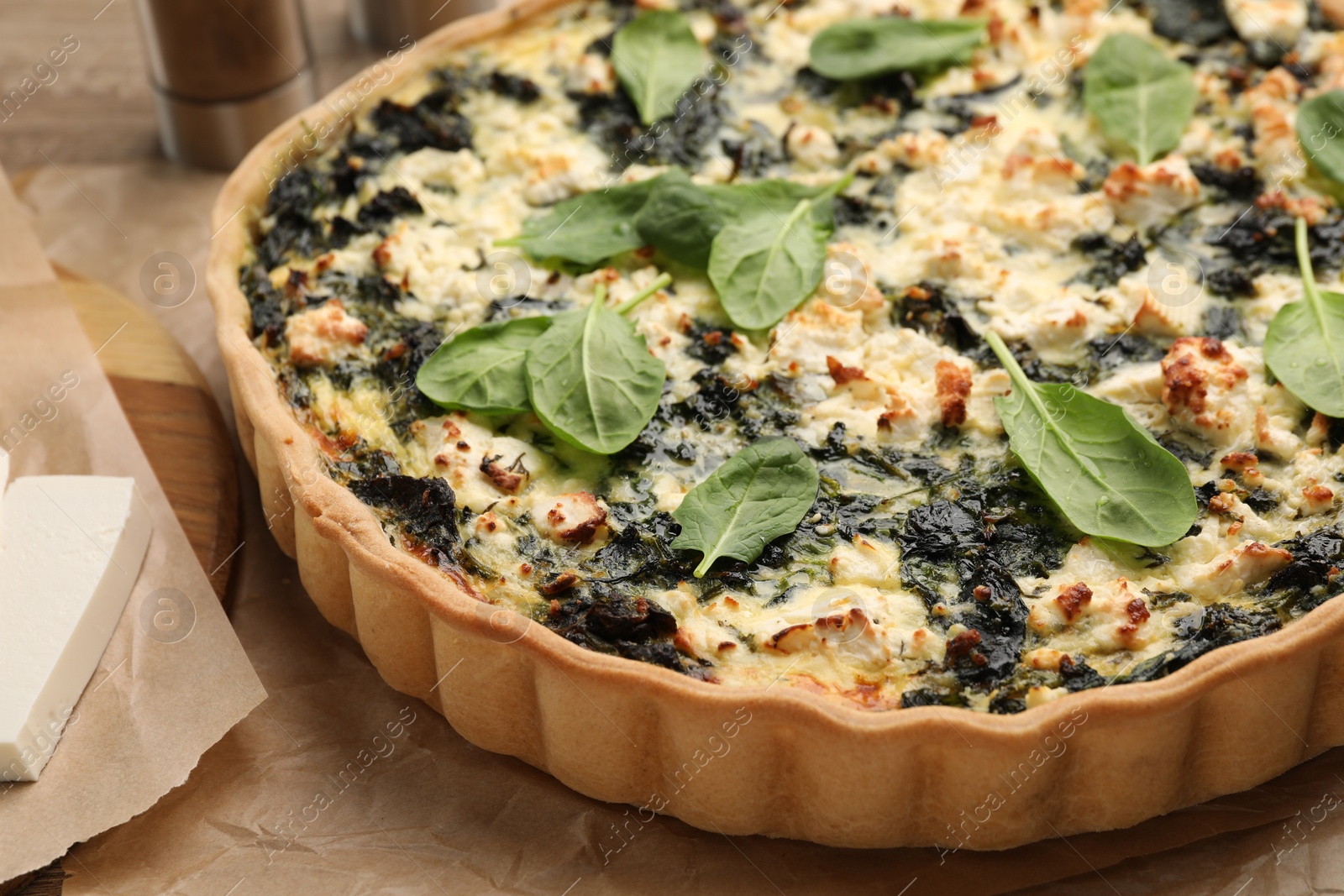 Photo of Delicious homemade spinach quiche parchment paper, closeup