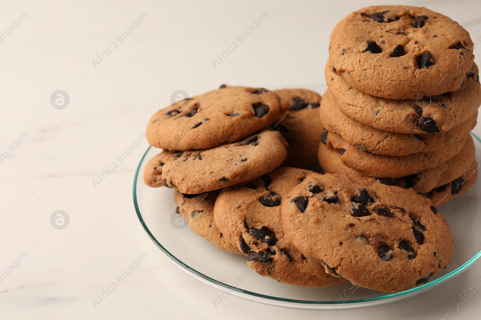 Photo of Delicious chocolate chip cookies on white marble table, closeup. Space for text