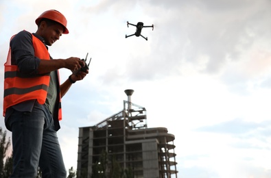 Photo of Builder operating drone with remote control at construction site. Aerial survey