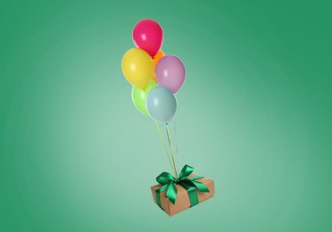 Many balloons tied to gift box on sea green background