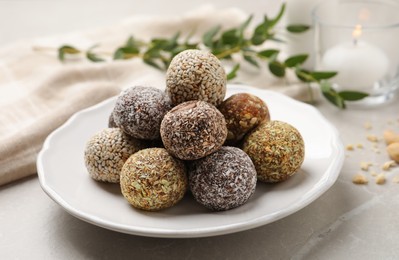 Photo of Different delicious vegan candy balls on light grey marble table