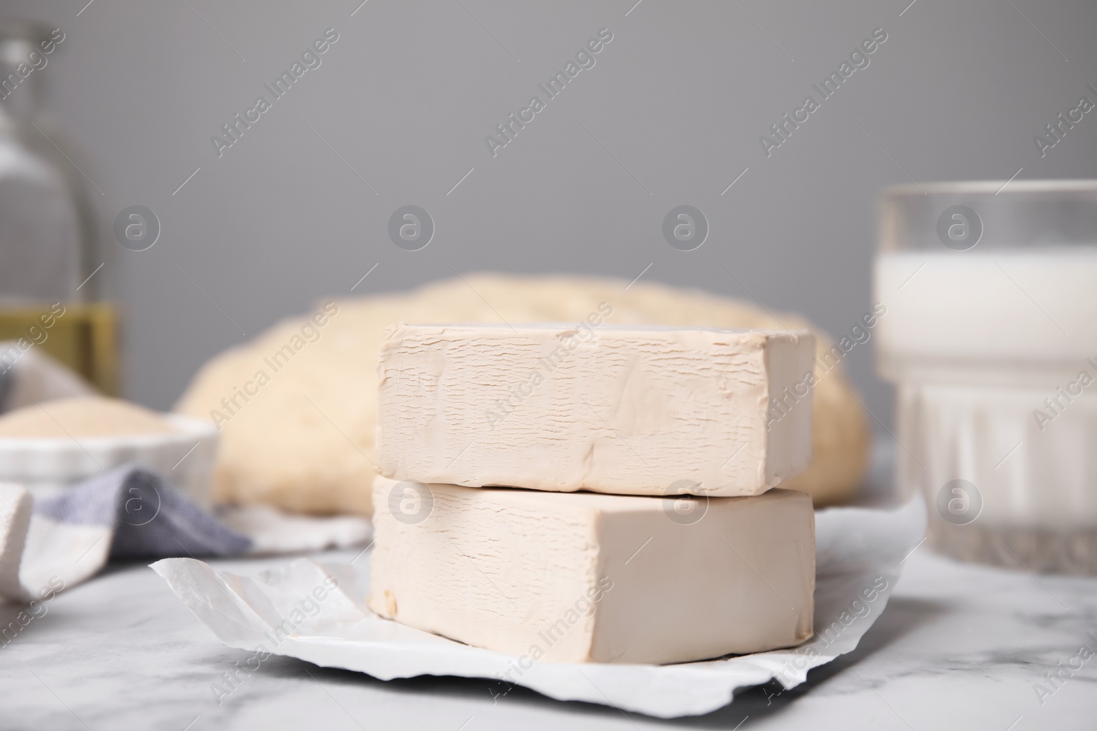 Photo of Blocks of compressed yeast on white marble table, closeup