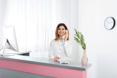 Photo of Beautiful woman talking on phone at reception desk in beauty salon