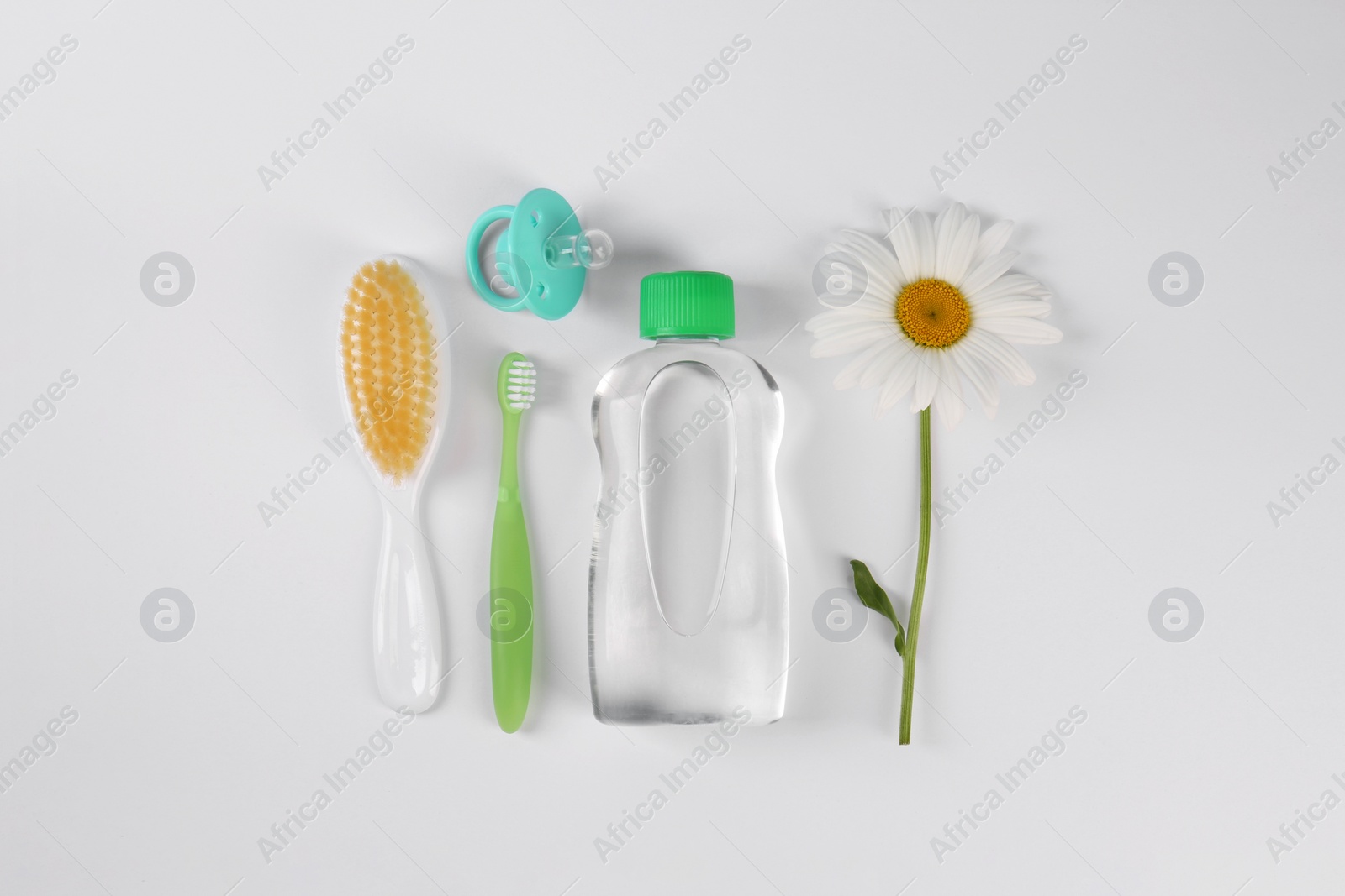 Photo of Bottle with baby oil, daisy and accessories on white background, flat lay