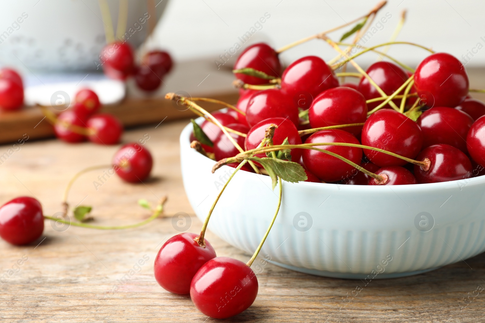 Photo of Bowl of delicious cherries on wooden table, closeup view. Space for text