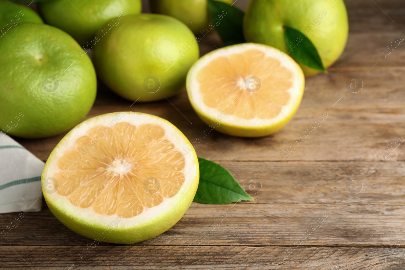 Photo of Whole and cut sweetie fruits on wooden table