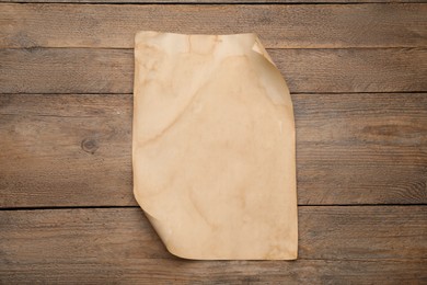 Photo of Sheet of old parchment paper on wooden table, top view. Space for design