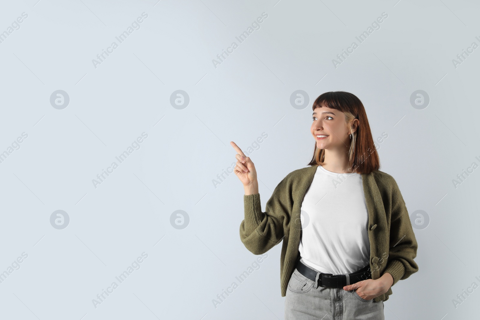 Photo of Beautiful young girl pointing on white background. Space for text