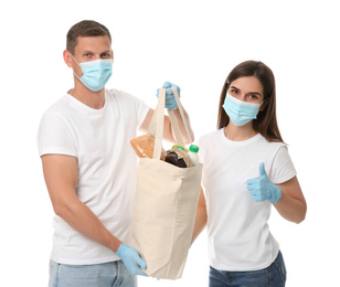 Photo of Volunteers in protective masks and gloves with products on white background. Aid during coronavirus quarantine