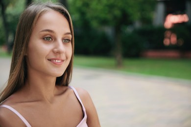 Portrait of beautiful young woman in park, space for text