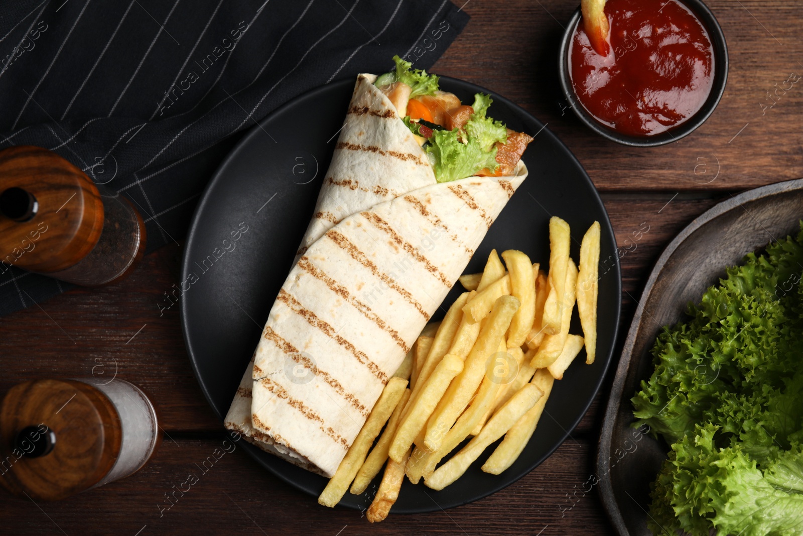 Photo of Delicious chicken shawarma and French fries served on wooden table, flat lay