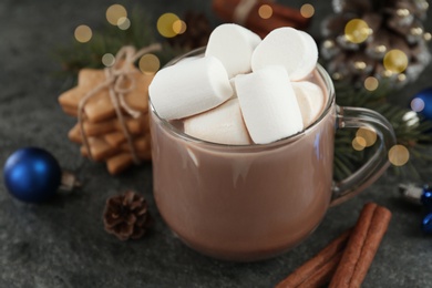 Photo of Delicious cocoa drink with marshmallows and Christmas decor on grey table, closeup