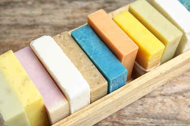 Many different handmade soap bars in wooden box on table, closeup