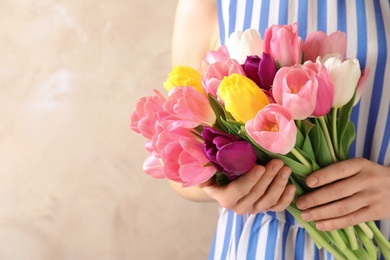 Photo of Girl holding bouquet of beautiful spring tulips on color background, closeup with space for text. International Women's Day