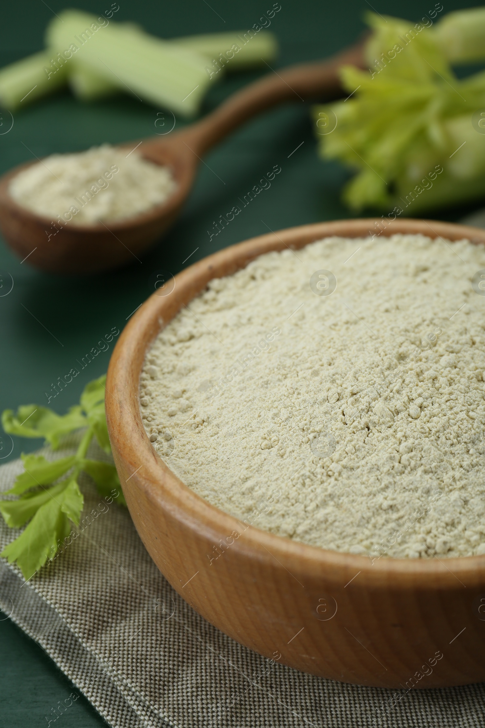 Photo of Natural celery powder and fresh stalks on green table, closeup