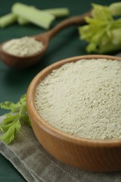 Photo of Natural celery powder and fresh stalks on green table, closeup