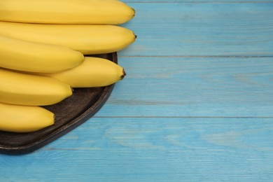 Photo of Ripe yellow bananas on light blue wooden table. Space for text