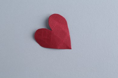 Photo of Red crumpled paper heart on gray background, top view