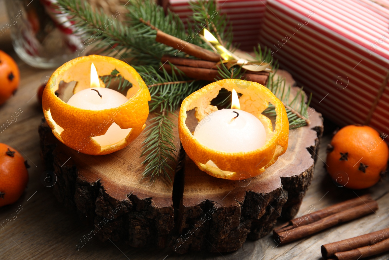 Photo of Composition with burning candles in tangerine peels as holders on wooden table