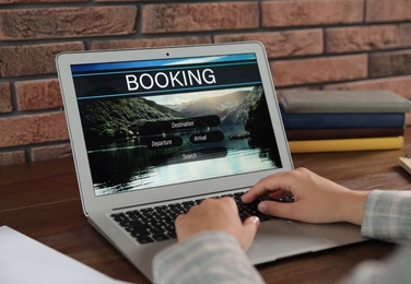 Young woman using laptop to plan trip, closeup. Travel agency website