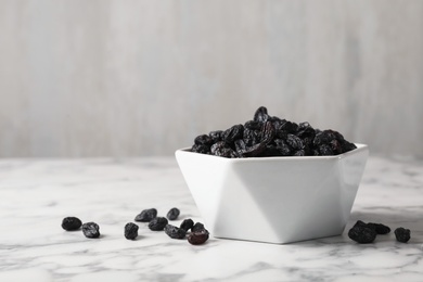 Photo of Bowl with raisins on marble table, space for text. Dried fruit as healthy snack