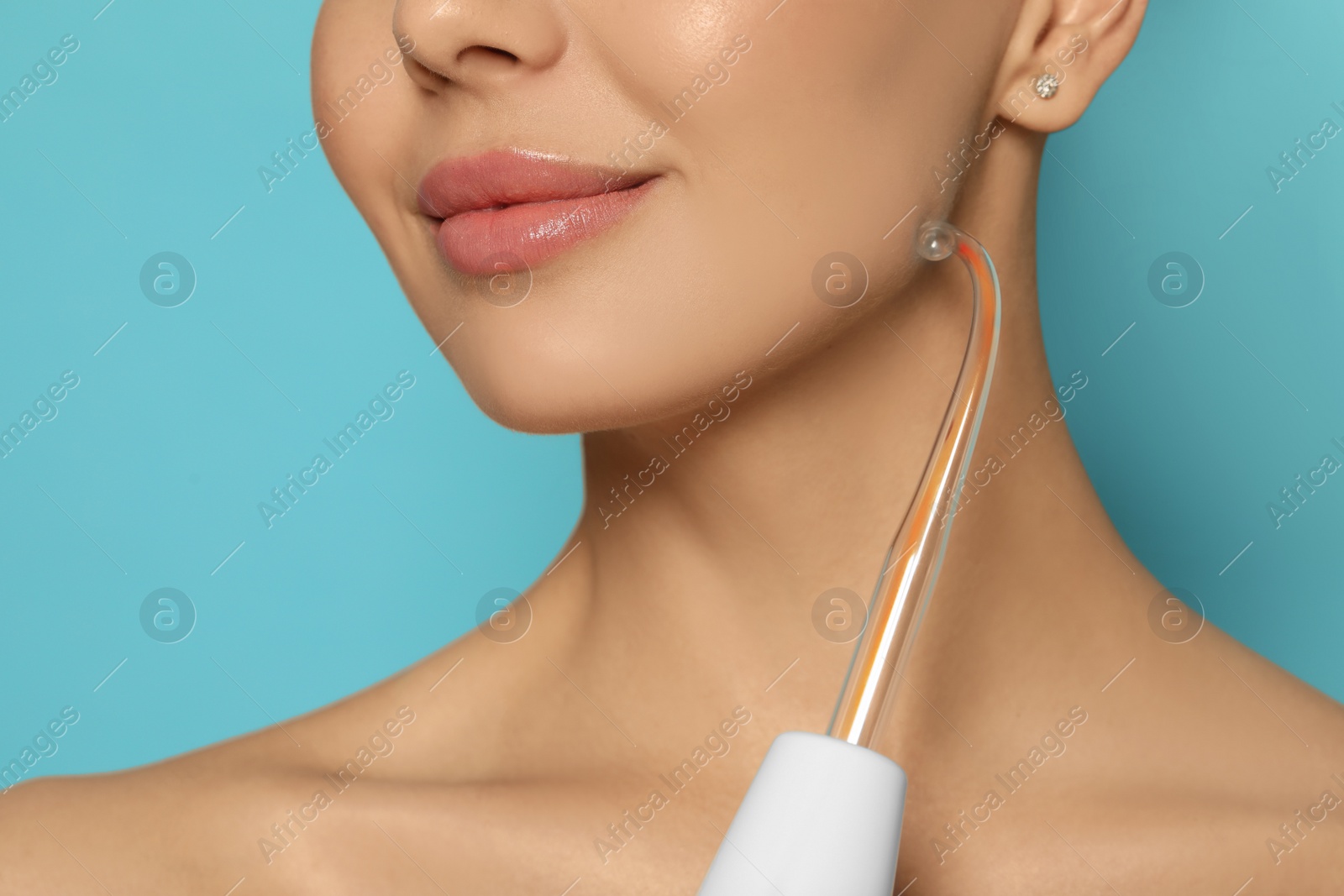 Photo of Woman using high frequency darsonval device on light blue background, closeup