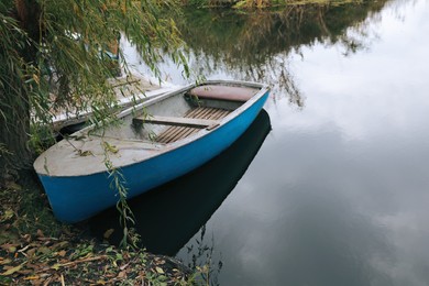 Photo of Light blue wooden boat on lake near pier, space for text