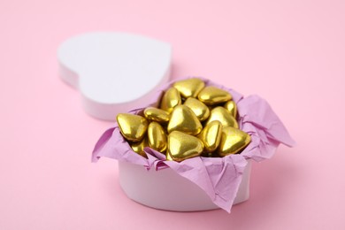 Box with delicious heart shaped candies on pink background