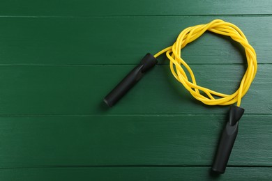 Skipping rope on green wooden table, top view. Space for text