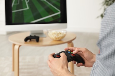 Photo of Young man playing video games at home, closeup