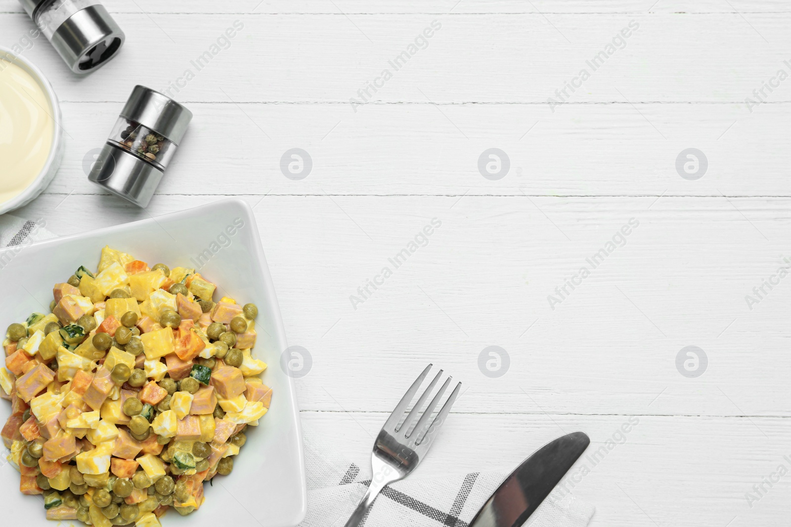 Photo of Delicious russian salad Olivier served on white wooden table, flat lay with space for text