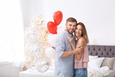 Young couple with air balloons in bedroom. Celebration of Saint Valentine's Day