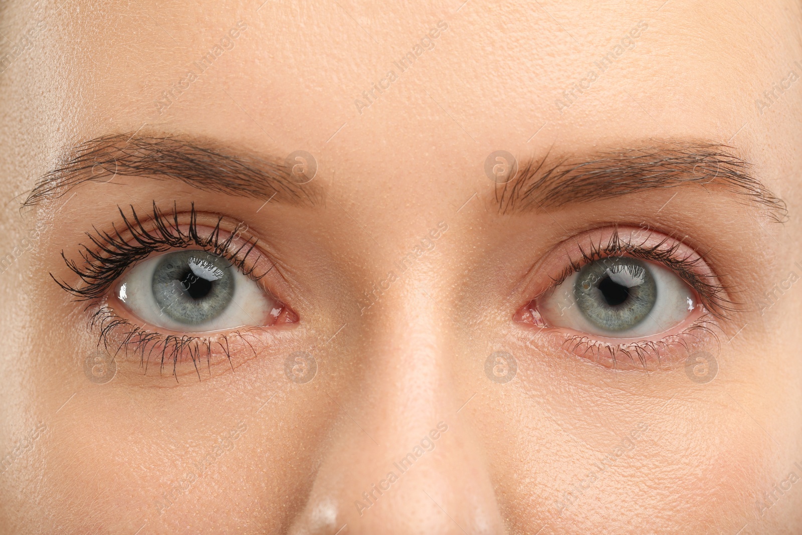 Photo of Woman showing difference in eyelashes length after mascara applying, closeup
