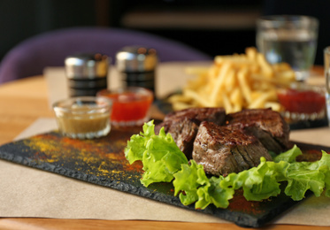 Photo of Tasty pieces of shish kebab served on slate plate in cafe