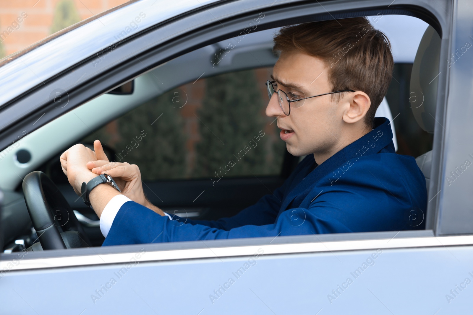 Photo of Young man checking time in car. Being late