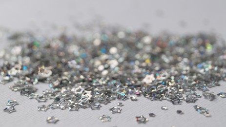 Photo of Pile of silver star shaped sequins on white background, closeup