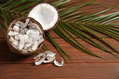 Tasty coconut chips on wooden table. Space for text