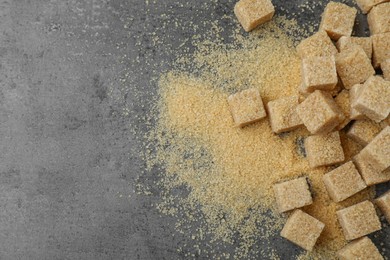 Photo of Brown sugar cubes on grey table, flat lay. Space for text