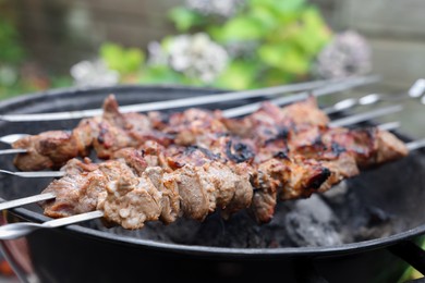 Photo of Cooking delicious kebab on metal brazier outdoors, closeup
