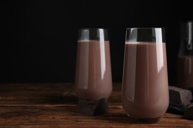 Delicious chocolate milk in glasses on wooden table