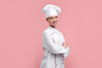 Photo of Young woman chef in uniform on pink background
