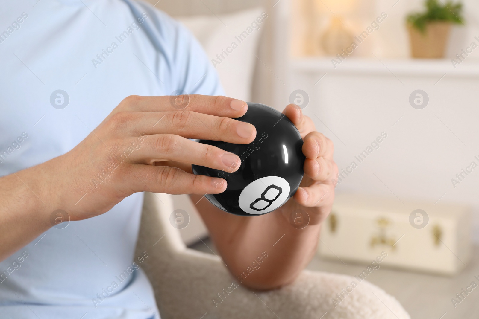 Photo of Man holding magic eight ball indoors, closeup