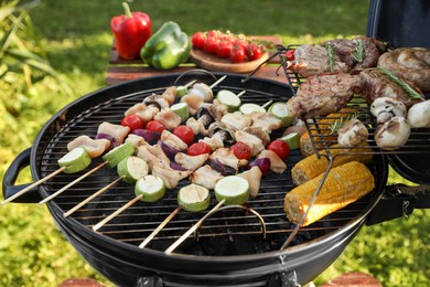 Photo of Cooking meat and vegetables on barbecue grill outdoors