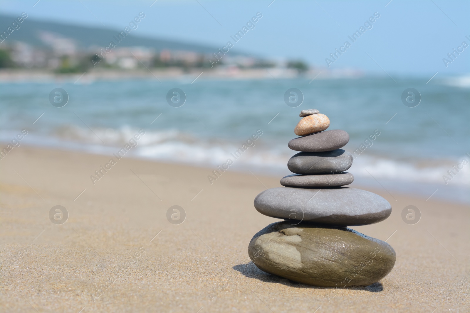 Photo of Stack of stones on sandy beach near sea, space for text