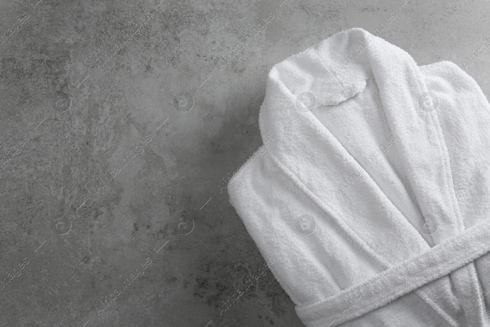 Photo of Clean folded bathrobe on grey stone background, top view. Space for text