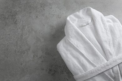 Photo of Clean folded bathrobe on grey stone background, top view. Space for text