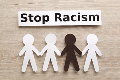 Photo of Phrase Stop Racism and paper figures on wooden table, flat lay