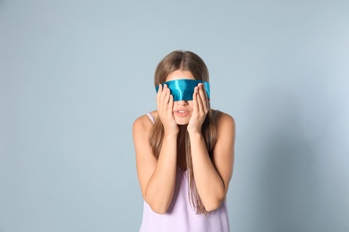 Young woman with light blue blindfold on grey background